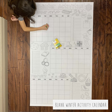 Blank winter activity calendar on a wooden floor with a child interacting with it.